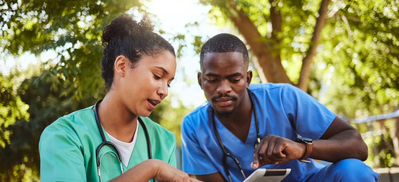 two nurses looking at a tablet and choosing where to work